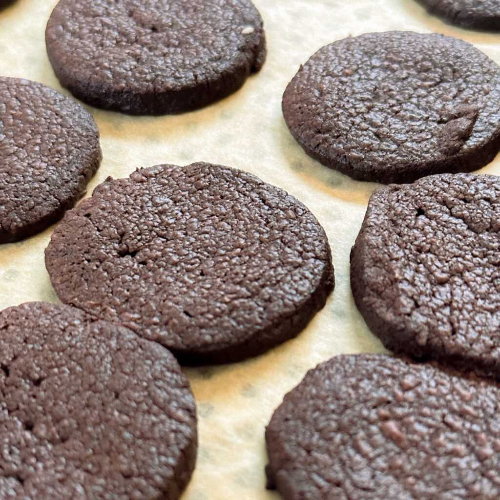 Bild von mehreren dunklen Schokokeksen auf einem Backblech.